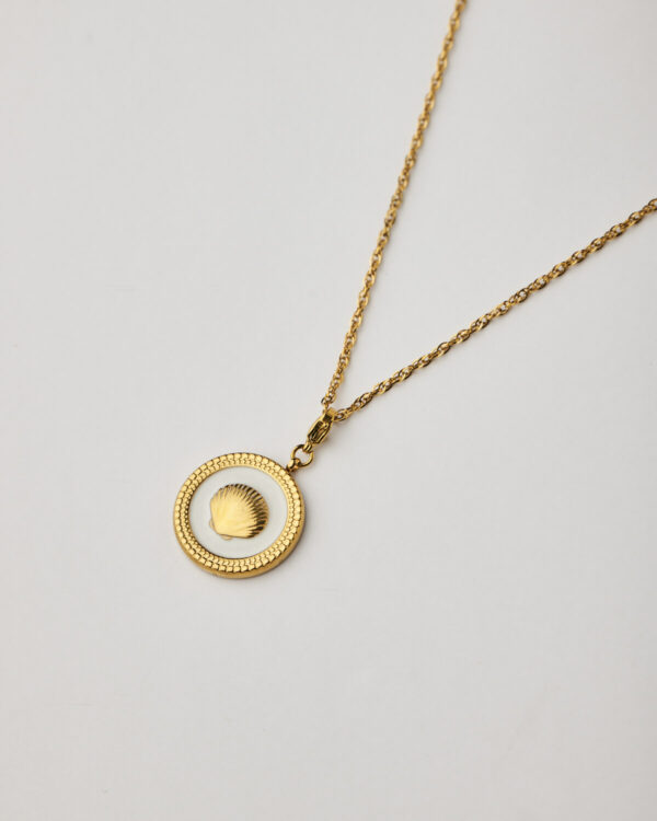 Close-up of gold medallion necklace with shell inside