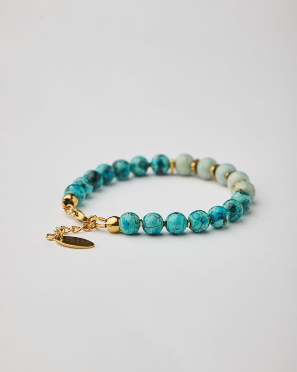 Close-up of bracelet with marble aquamarine howlite in two tones and gold clasp