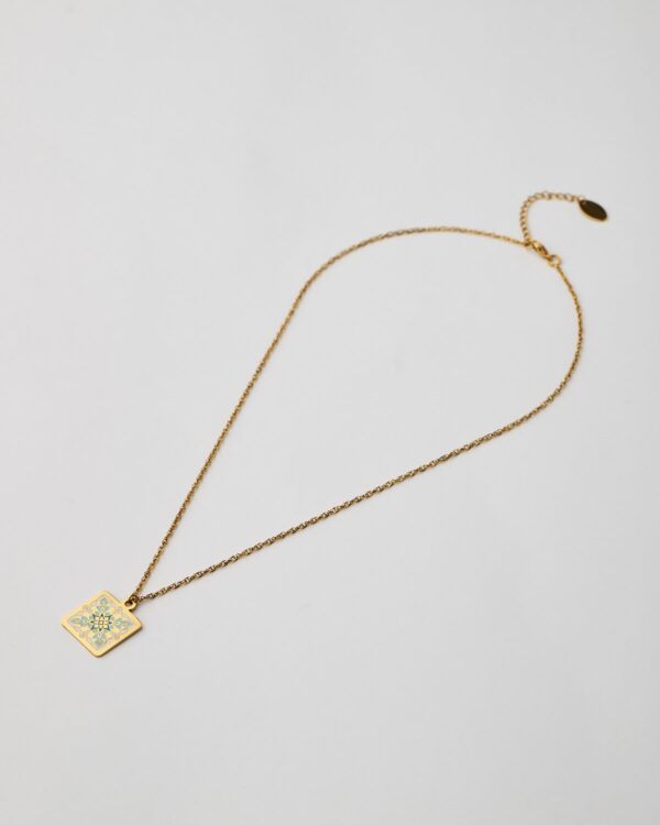 Close-up of mandala enamel pendant in aqua and gold tones