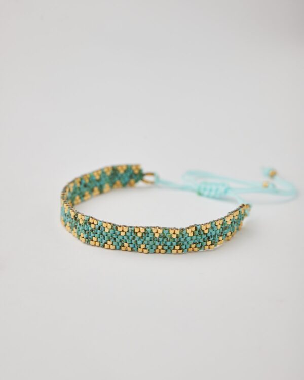 Close-up of Miyuki friendship bracelet with turquoise and gold chevron pattern