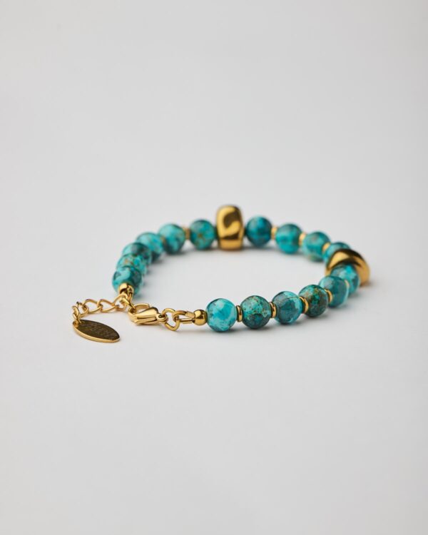 Close-up of handmade bracelet with marble aquamarine howlite beads and gold clasp