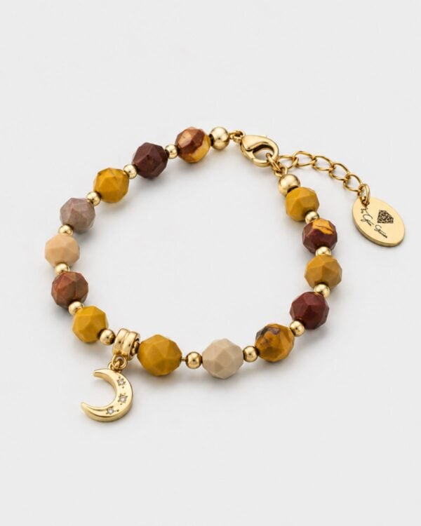 Natural jasper gemstone bracelet featuring faceted beads in earthy tones of ochre, terracotta, and sand, accented with gold-plated sphere spacers and a central gold crescent moon charm set with tiny sparkling crystals on a white background.