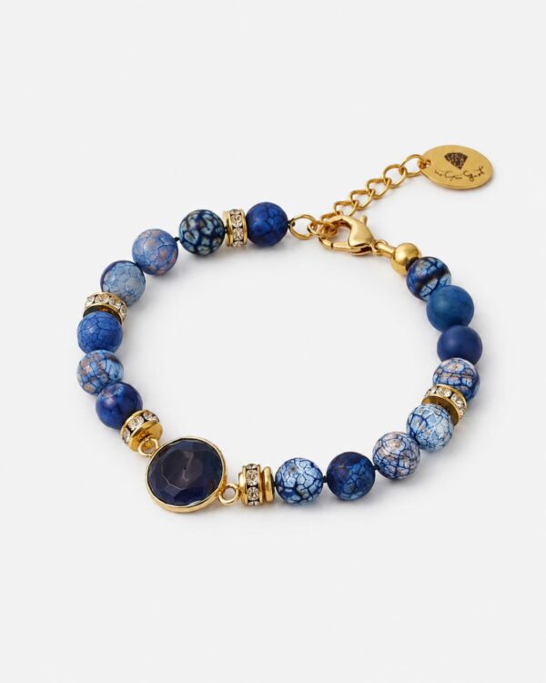 Blue agate bracelet with gemstone element and gold accents on a white background