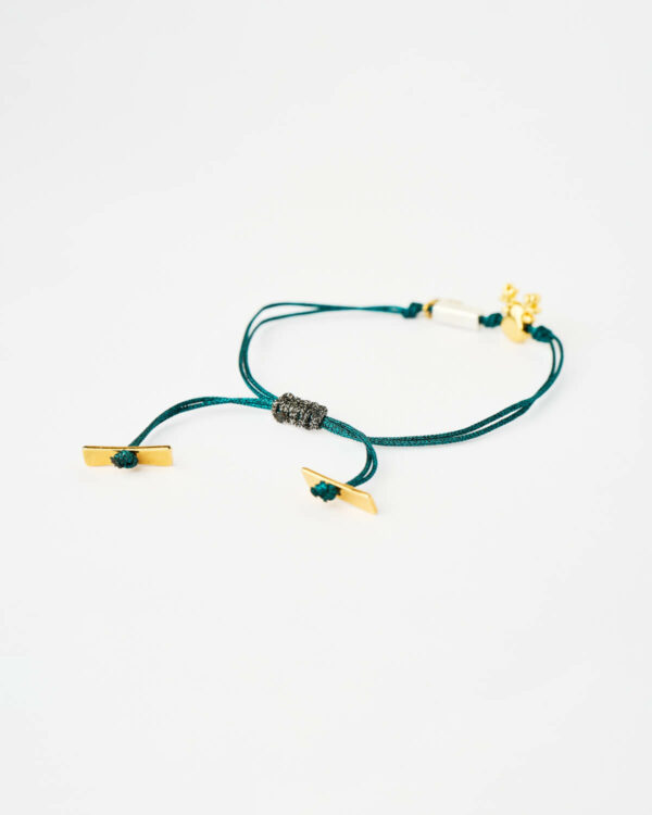 Closeup of the Reindeer Evil Eye Bracelet in blue cord with gold reindeer charm and turquoise evil eye bead by The Gem Stories