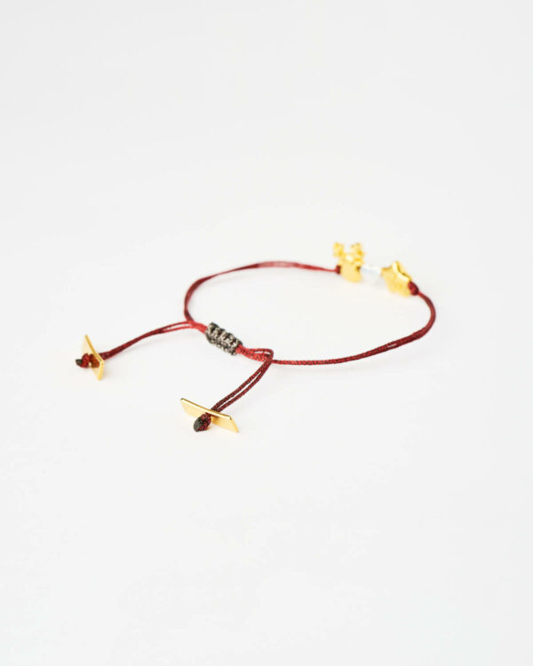 Close-up of the Reindeer Star Charm Bracelet in red with gold-tone star and reindeer charms by The Gem Stories