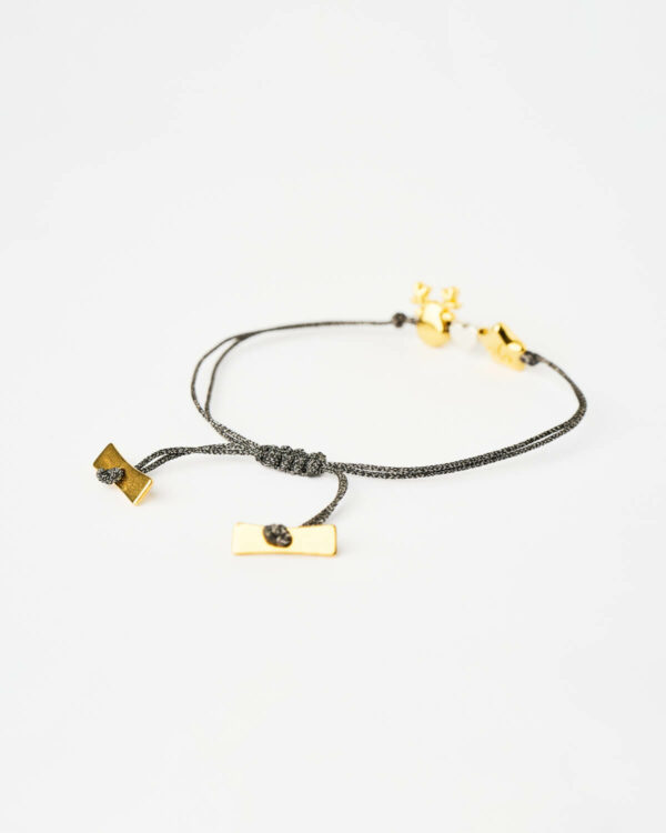 Close-up of the Reindeer Star Charm Bracelet in black with gold star and reindeer charms by The Gem Stories