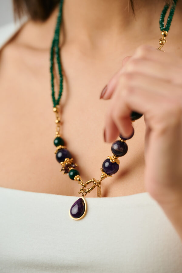 Κοντινή λήψη κολιέ με αμέθυστο και πράσινο νεφρίτη με χρυσό μενταγιόν σε σχήμα σταγόνας