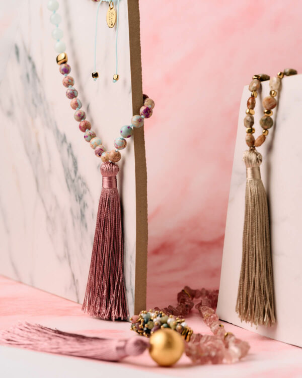 Editorial λήψη από boho κολιέ με φούντα, με φυσικές πέτρες και χρυσές λεπτομέρειες.