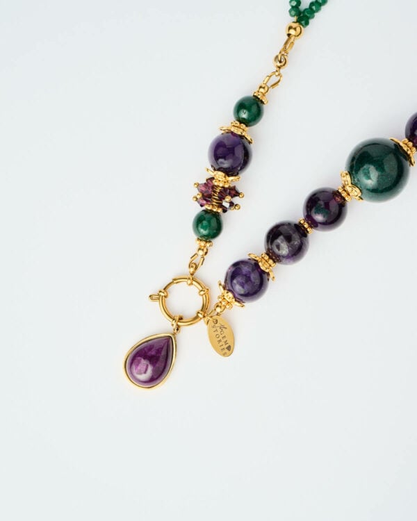 Κοντινή λήψη του Κολιέ Emerald Aura με πράσινες χάντρες, μωβ πέτρες και χρυσές λεπτομέρειες από τη The Gem Stories.