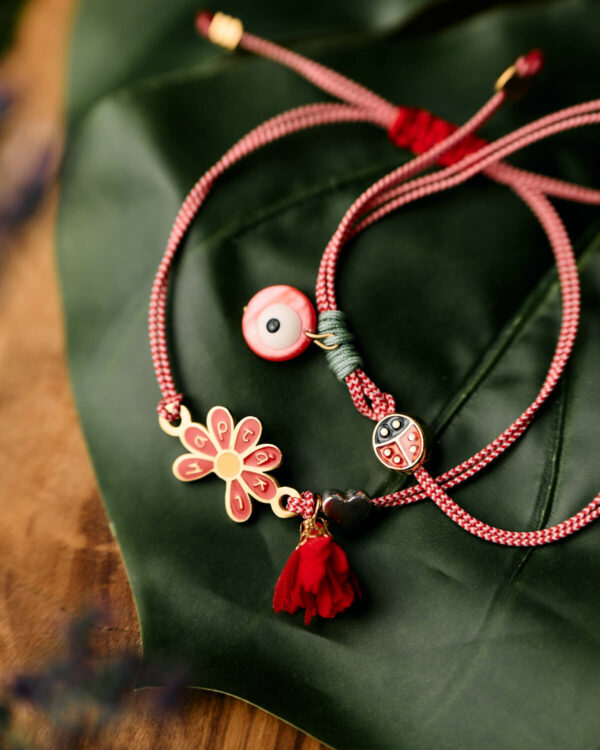 Κόκκινο και λευκό μαρτάκι με μοτίφ λουλουδιού, μοτίφ πασχαλίτσας και χάντρα ματιού.