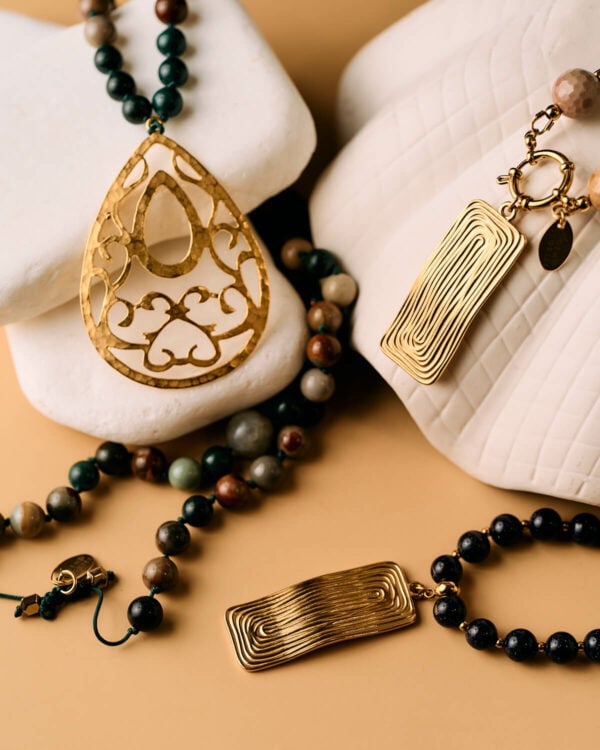 Κολιέ με εντυπωσιακά χρυσά μενταγιόν και χάντρες από φυσικούς πολύτιμους λίθους σε ουδέτερο φόντο