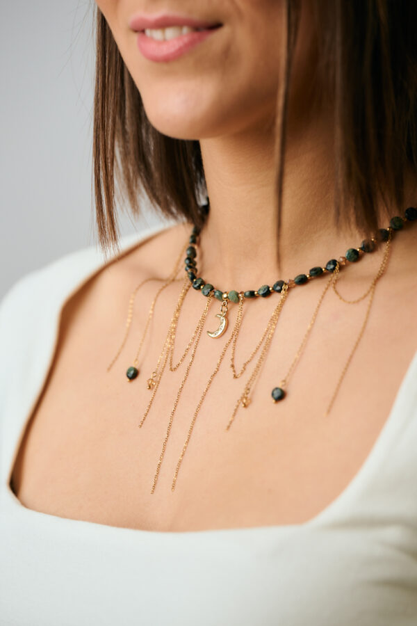 Λεπτομερής κοντινή λήψη του κολιέ Green Gemstone Layered Moon με πράσινες πέτρες και χρυσές αλυσίδες από το The Gem Stories.