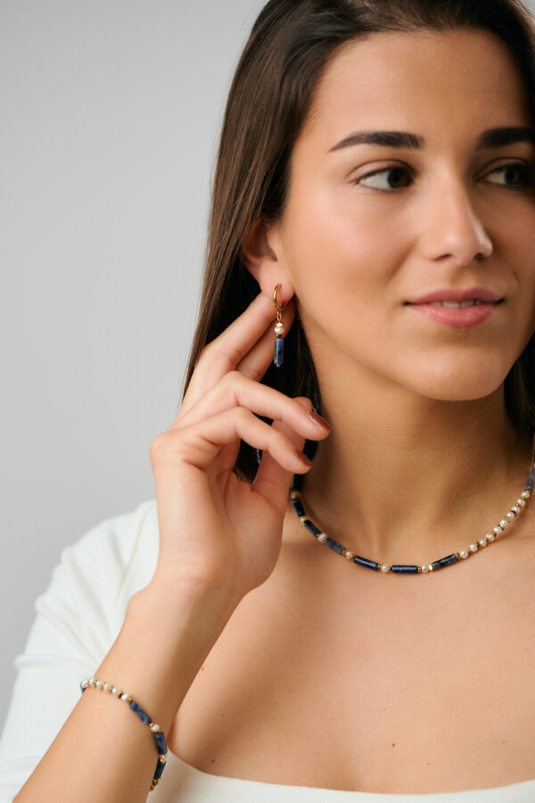 Μοντέλο που φορά κολιέ, σκουλαρίκια και βραχιόλι Λάπις Λάζουλι με Μαργαριτάρι και Χρυσό από το The Gem Stories