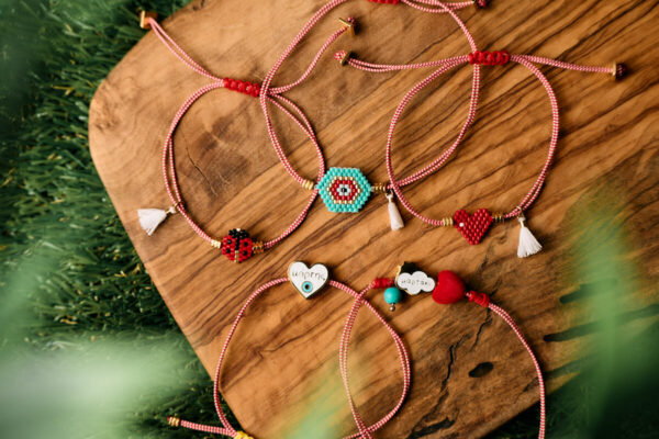 Βραχιόλια Μαρτάκι με γούρι μάτι, καρδιά και πασχαλίτσα σε ξύλινη επιφάνεια