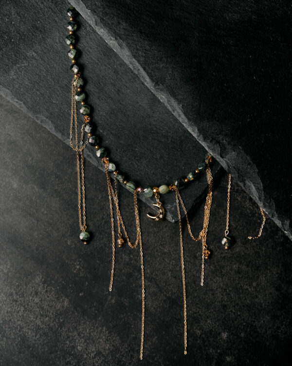 Κολιέ με σκούρες πράσινες πέτρες, χρυσές αλυσίδες και μοτίφ μισοφέγγαρου.