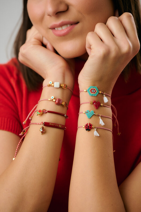 Model wearing multiple red Martaki bracelets with charms by The Gem Stories