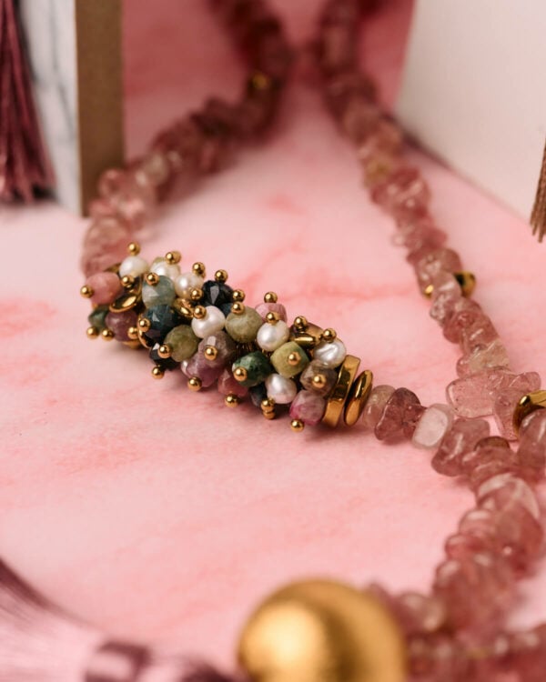 Κοντινό πλάνο κολιέ από ροζ χαλαζία με κεντρικό κομμάτι από σύμπλεγμα πολλαπλών λίθων και χρυσές λεπτομέρειες