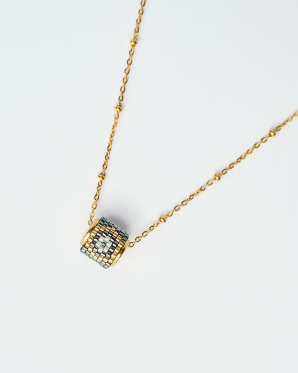 Κοντινή λήψη του κολιέ Miyuki Round Evil Eye σε απόχρωση gunmetal με χρυσή αλυσίδα, χειροποίητο από το The Gem Stories