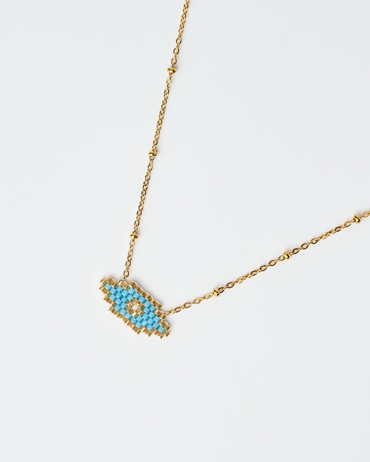 Κοντινή λήψη του λεπτεπίλεπτου μπλε κολιέ Miyuki Evil Eye Κοντινή λήψη του Λεπτού Κολιέ Miyuki Evil Eye σε μπλε απόχρωση με χρυσή αλυσίδα, χειροποίητο από το The Gem Stories