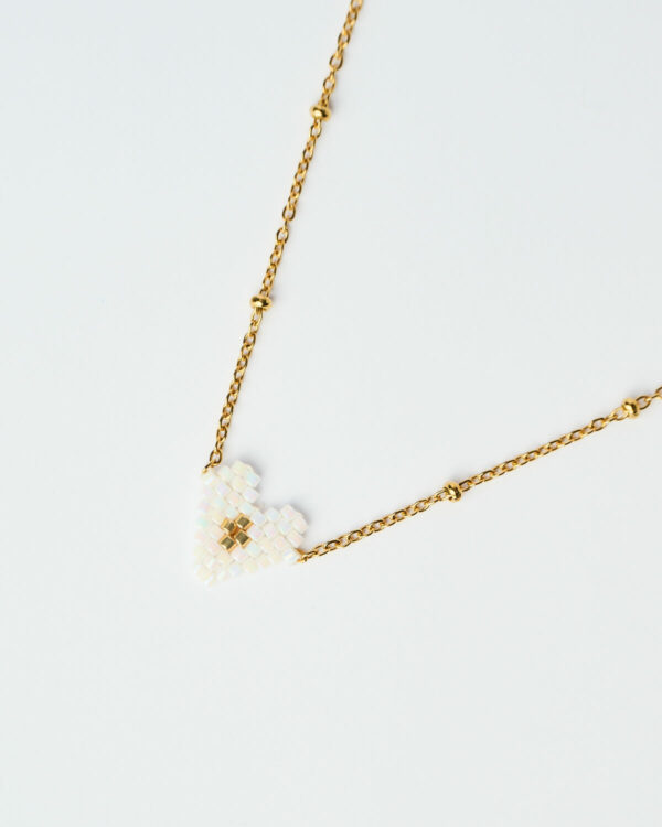 Κοντινή λήψη του Delicate Miyuki Heart Necklace σε λευκό, με χρυσή αλυσίδα, χειροποίητο από το The Gem Stories