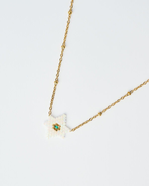 Κοντινή λήψη του Delicate Miyuki Star Necklace σε λευκό, με χρυσή αλυσίδα, χειροποίητο από το The Gem Stories
