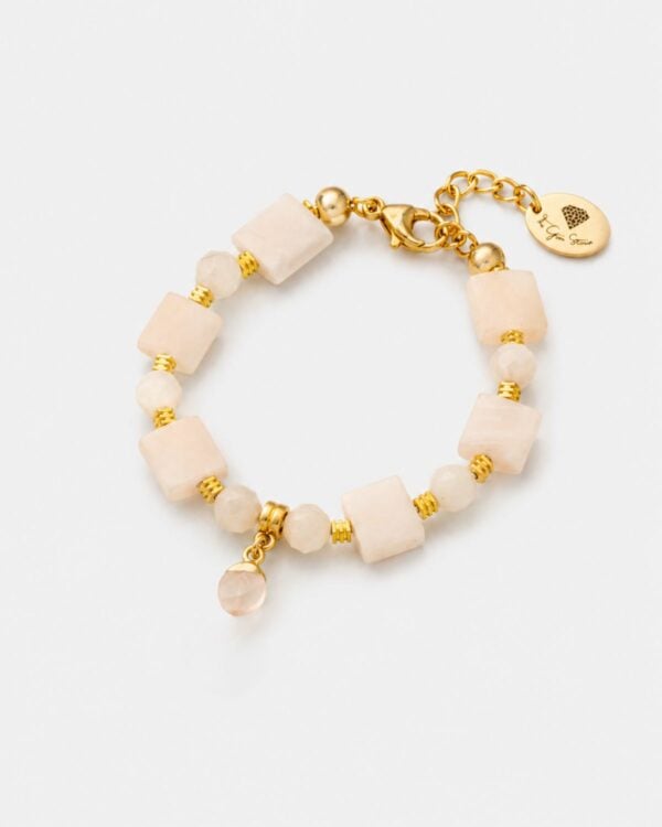 Χειροποίητο βραχιόλι Blush Rose Quartz που απεικονίζεται στο αρχείο Screenshot 2026-05-13 at 9.43.19 AM_2.png, με συνδυασμό από τετράγωνες και πολύπλευρες στρογγυλές χάντρες απαλού ροζ χαλαζία, διακοσμημένο με επιχρυσωμένα ραβδωτά spacers, κούμπωμα τύπου αστακού και χρυσή υπογραφή-ετικέτα με λογότυπο σε σχήμα διαμαντιού, σε λευκό φόντο.